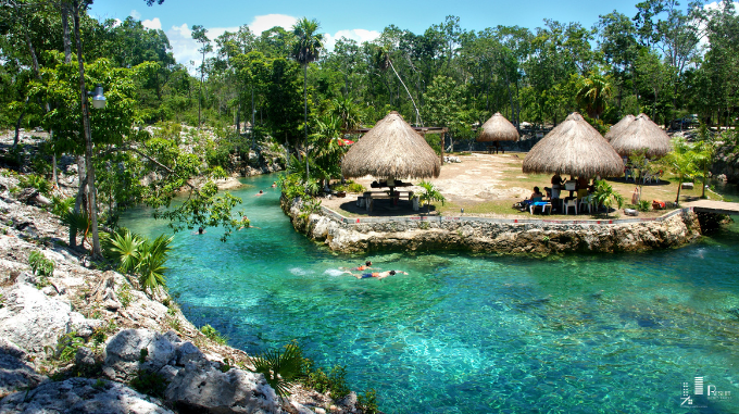 Vista aérea de una playa paradisíaca en Tulum con arena blanca, mar turquesa y una villa ecológica rodeada de palmeras. Representa el estilo de vida caribeño, la sostenibilidad y el lujo que caracteriza a Tulum como destino ideal para vivir o invertir.